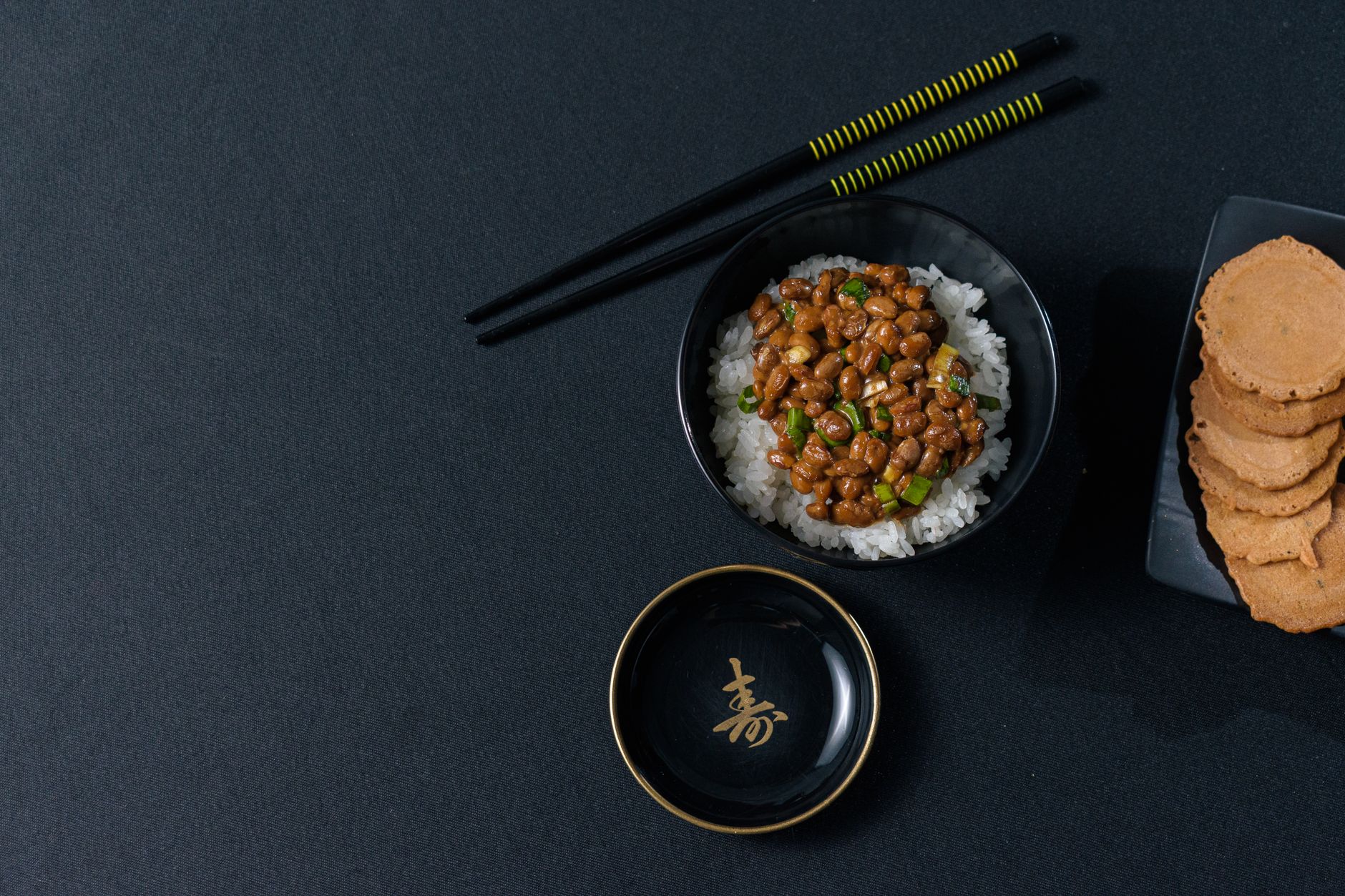 黒い器に盛られたご飯と箸、ふるさと納税の返礼品をイメージした和食の食卓