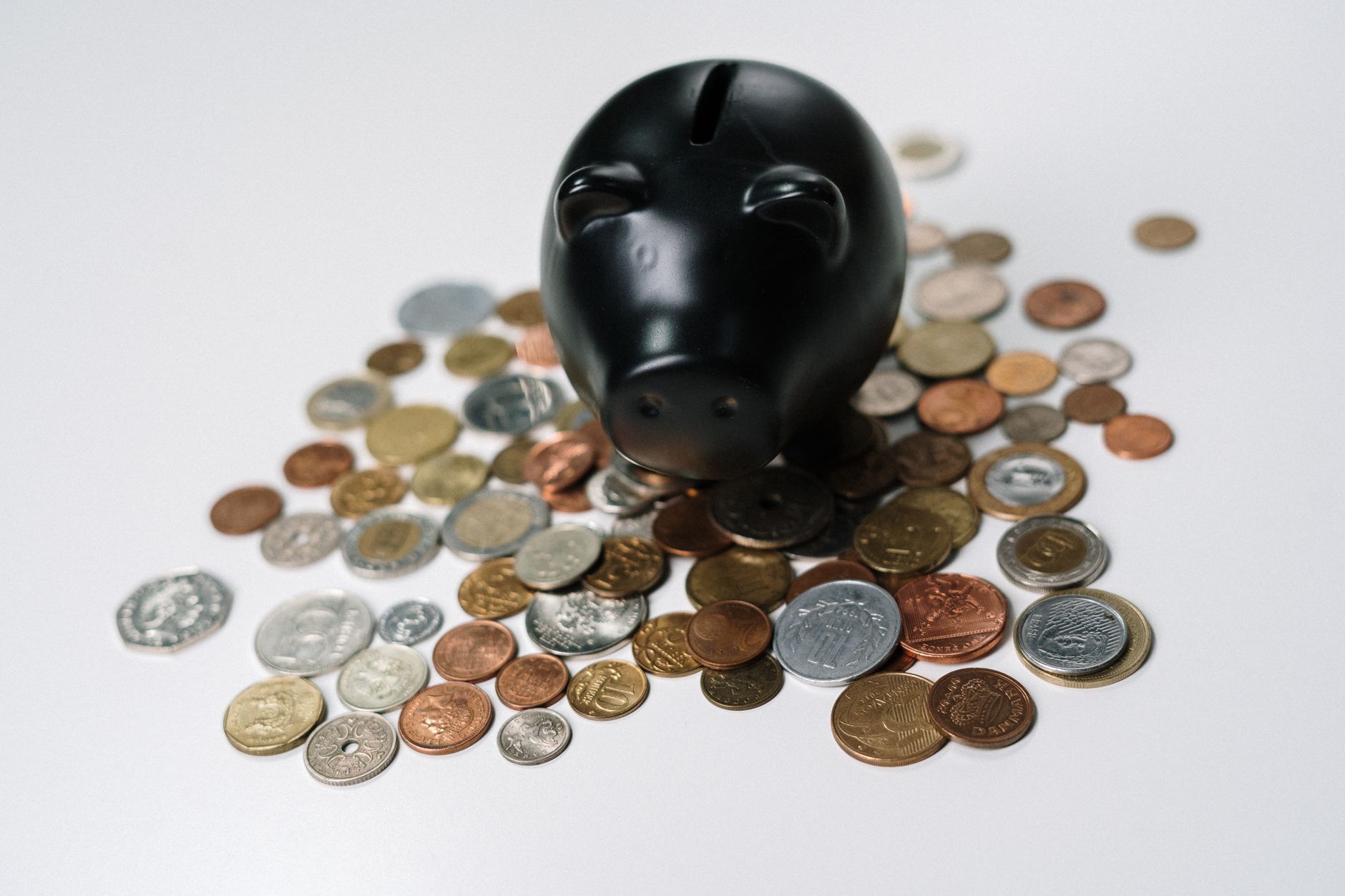 黒い貯金箱と硬貨、先取り貯金のイメージ